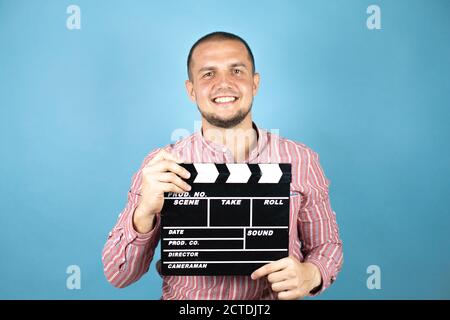 Russian business man over blue background holding clapperboard very happy having fun Stock Photo