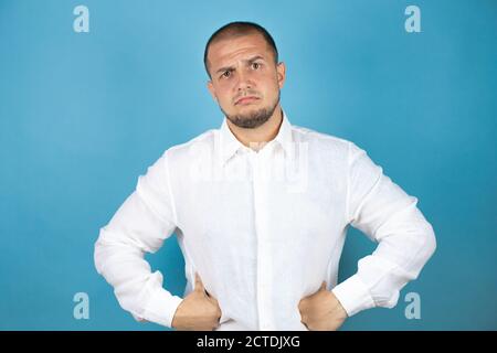 Skeptic And Nervous Man In White T-shirt On Dark Gray Background Stock 