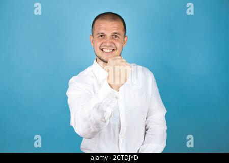 Russian business man wearing white shirt standing over blue background very happy and excited making winner gesture with raised arms, smiling and scre Stock Photo