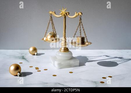 Cost of Christmas holidays concept. Weight scales, vintage balance with stack of coins and Xmas trinkets. Stock Photo
