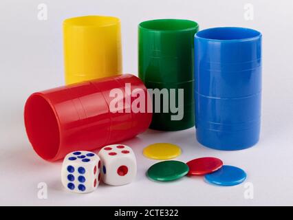 Used dices, tokens and shaking cups of color on a white surface Stock Photo