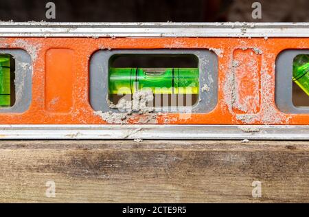 Dirty orange tool level in use, closeup. Also know as Tubular Spirit Level or Bubble Level. Used to find a true horizontal or vertical plane. Stock Photo