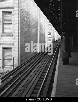 View of a lone passenger waiting on an elevated railway platform. At this Bronx location, the tracks tightly crowd tenement buildings as far as the eye can see, New York, NY, 1953. (Photo by United States Information Agency/RBM Vintage Images) Stock Photo