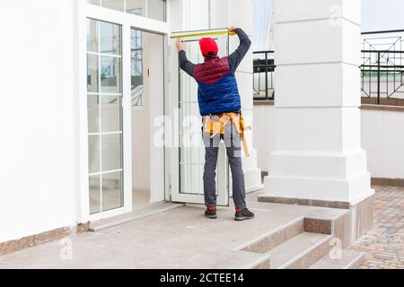 Builder mounting electric wiring on the building facade for outdoor lighting Stock Photo