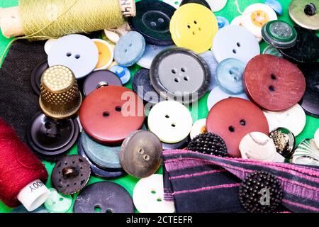 multicolored buttons, two spools of thread and a thimble are on the table Stock Photo