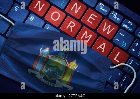 COVID-19 coronavirus new normal concept in the US state of New York as shown by its state flag on face mask with New Normal on laptop red alert keyboa Stock Photo