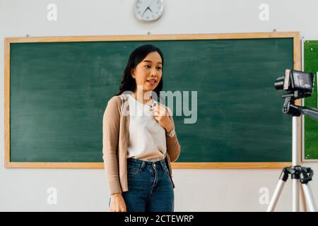 Young woman providing remote lesson using video camera, technology, remote learning, online education. Asian school teacher delivering online course Stock Photo