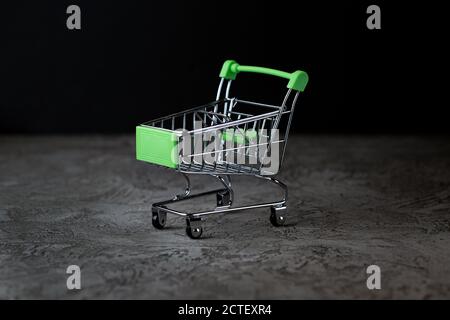 An empty grocery basket stands on the gray stone floor. On a black background. Stock Photo