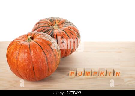 two pumpkins on a wooden table. the word PUMPKIN is laid out in wooden cubes. agriculture pamkin concept Stock Photo