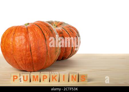 two pumpkins on a wooden table. the word PUMPKINS is laid out in wooden cubes. agriculture pamkin concept Stock Photo