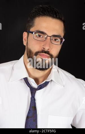 Portrait of handsome young bearded man with glasses in formal wear. Optical male model. Attractive stylish businessman with tie and shirt. Black backg Stock Photo