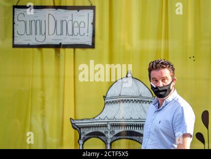 The changing face of the high street. A man holds a cigarette in his mouth while wearing a protective face mask, walking along the high street in Dundee in Scotland, some six months on from the evening of March 23 when Prime Minister Boris Johnson announced nationwide restrictions. Stock Photo