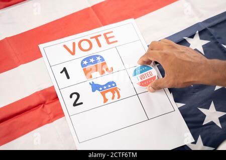 Hands placing I voted Sticker on democratic party symbol - concept of voting to democrats at US election Stock Photo