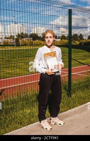 https://l450v.alamy.com/450v/2ctf9k1/young-girl-stand-near-school-fence-and-hold-sketch-book-and-album-girl-in-white-blouse-pink-backpack-2ctf9k1.jpg