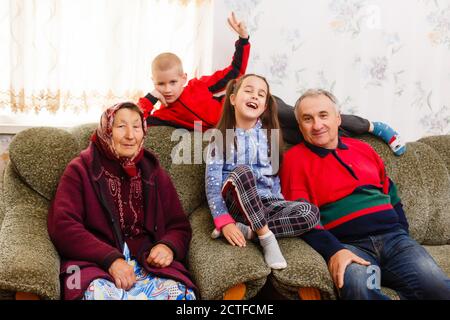 Grandchildren jumping on couch with their grandparents in the living room Stock Photo