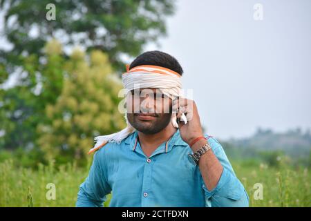 TIKAMGARH, MADHYA PRADESH, INDIA - SEPTEMBER 15, 2020: Indian farmer using mobile phone at sesame field. Stock Photo