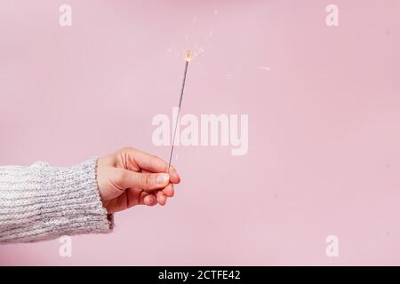 Female hand in sweater holding festive Christmas sparkler Stock Photo