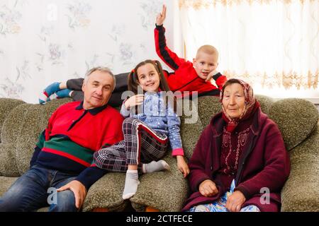 Grandchildren jumping on couch with their grandparents in the living room Stock Photo