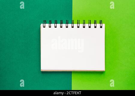 Top view of open empty spiral notebook on green colorful background Stock Photo
