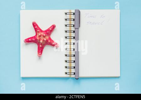 Top view of open empty notebook with starfish and "time to travel" inscription on pastel blue colorful background. Travel and holiday concept Stock Photo