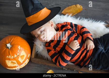 Baby boy with halloween hat, sleeping in a basket, halloween decoration around him Stock Photo