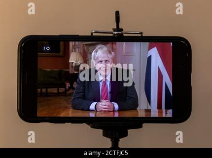 London, UK. 22nd Sep, 2020. Photo taken on Sept. 22, 2020 shows a mobile phone broadcasting British Prime Minister Boris Johnson addressing the nation on TV in London, Britain. British Prime Minister Boris Johnson on Tuesday announced new restrictive measures to tackle a sharp rise in the country's coronavirus cases. Johnson confirmed that from Thursday, all pubs, bars and restaurants in England must operate a table service only -- except for takeaways -- and will be forced to close at 10:00 p.m. BST (2100 GMT). Credit: Han Yan/Xinhua/Alamy Live News Stock Photo