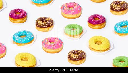 Creative pattern with sweet glazed donuts with different flavors on white background. Junk food. Stock Photo