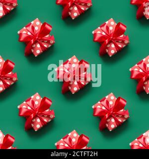 Seamless pattern of gifts in red and white packaging with polka dots and red bow on green background. Christmas giftboxes. Holday greeting card. Stock Photo