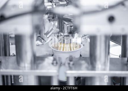 Automatic filling of sour cream into packaging. Machine milk industry equipment dairy plant Stock Photo