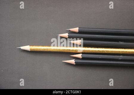 Black pencils and golden one among them on black background. Leadershio business career concept Stock Photo