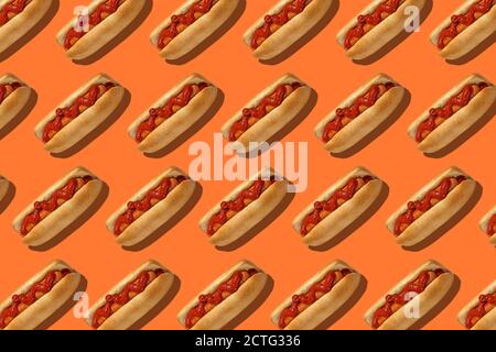 Delicious fast food for lunch in menu. Hot dogs with bun, sausage and red ketchup on orange background Stock Photo