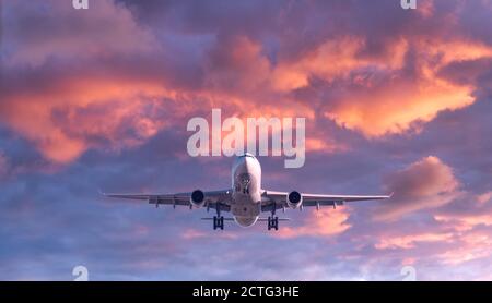 Passenger airplane is flying in colorful sky at sunset
