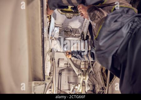Low angle portrait of seriously responsibility engineer doing plan modernization on the passenger aircraft while using special equipments and tools Stock Photo