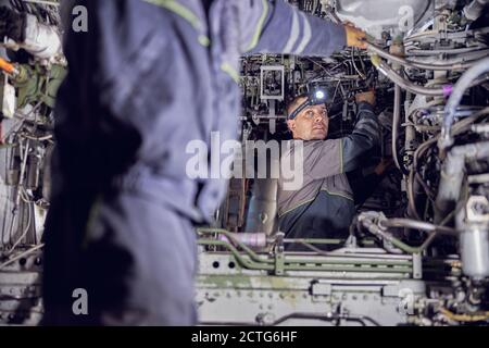 Close up portrait of handsome confident male with light on his head while working with inside system of passenger airplane Stock Photo