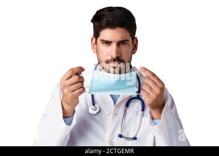 Shot of male doctor putting on face mask while standing at isolated white background. Stock Photo