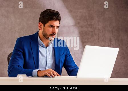Cropped shot of stressed businessman sitting at desk behind his laptop and looking thoughtfully while working in the office. Stock Photo