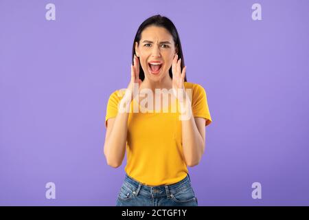 Lady holding hand near mouth, screaming at camera Stock Photo
