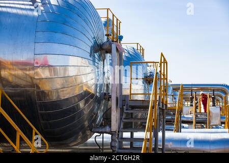 Close-up of a few heat exchangers . Oil refinery (Petrochemical) plant. Blue sky background. Worker in red work wear and white helmet adjusting  proce Stock Photo