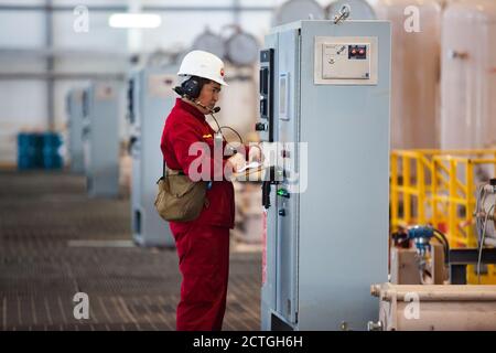 Aktobe region/Kazakhstan - May 04 2012: Oil refinery plant. Pumping station. Asian worker in red work wear and white hardhat controls the measuring de Stock Photo
