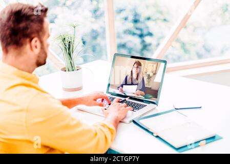 Businessman sitting behind his laptop and having discussion and online meeting in video call while working from home. Home office. Stock Photo