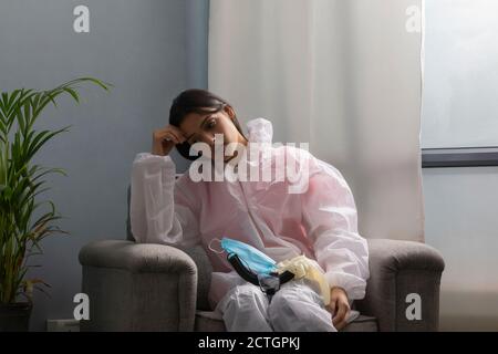 Female doctor in protective suit taking rest after attending covid patients Stock Photo