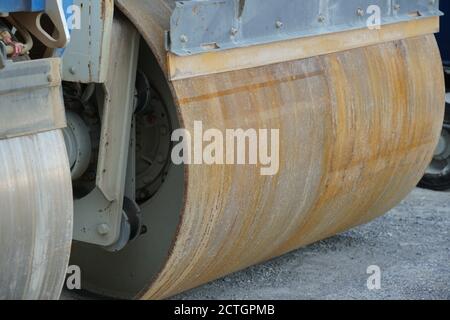 Close up view on forward drum of paver smooth drum roller as a heavy engineering equipment during weekend days near construction site of new road. Stock Photo