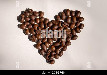 Heart formed with coffee beans on a creamy white background Stock Photo