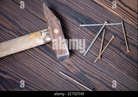 Old vintage hammer and nails on a wooden background, close-up, selective focus Stock Photo