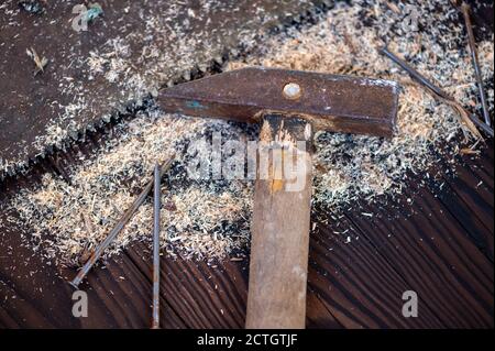 Old vintage hammer, wood saw, nails and sawdust on a wooden background, close-up, selective focus Stock Photo