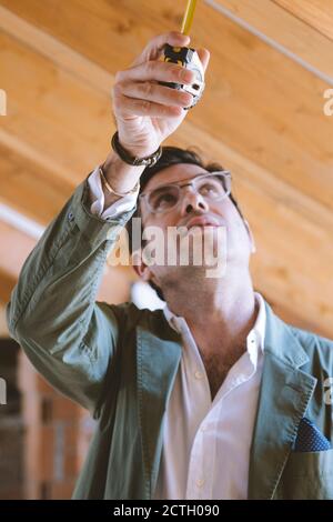 Architect at work looking up with a measuring tape in his hand Stock Photo