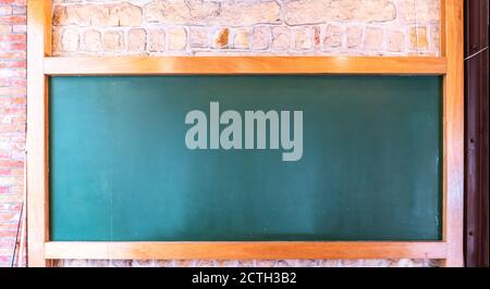 Blank blackboard on plank wooden table top at wall,Template mock up for adding your design and leave space beside frame for adding more content. Stock Photo