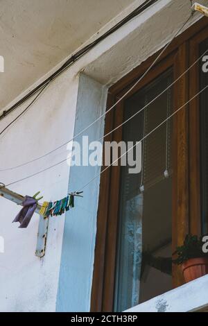 Colourful plastic wet cloth drying clip clamp hanging from a white wire on a balcony. Stock Photo