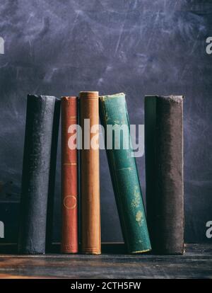 Old books on a wooden shelf, black board background. Law, history library shelf, vertical shot Stock Photo