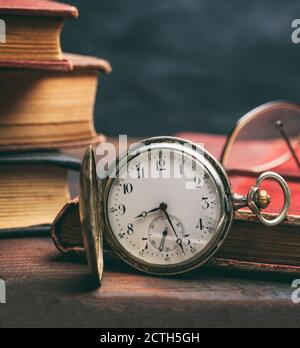 Vintage pocket watch and old books on a wooden office desk background. Time, science concept Stock Photo